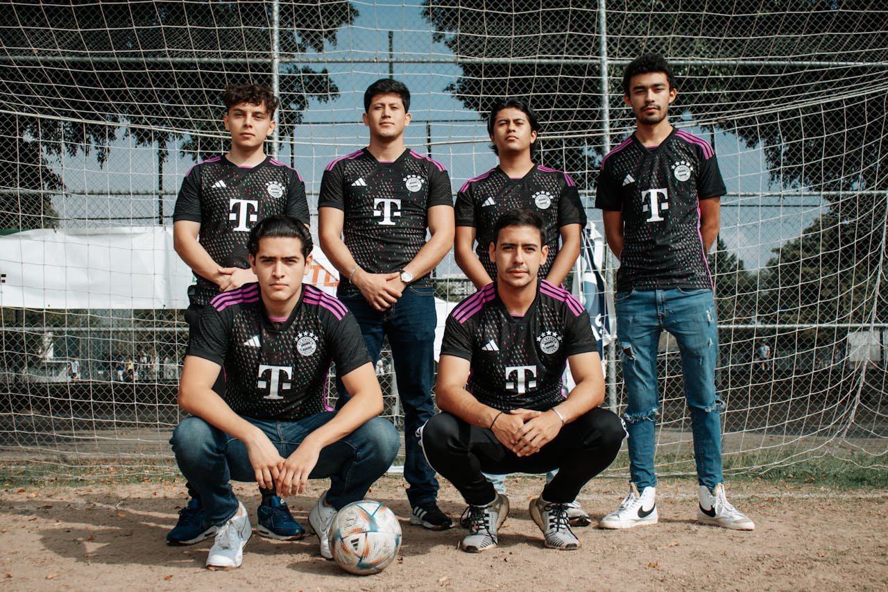 A group of men in team uniforms posing on a soccer field.